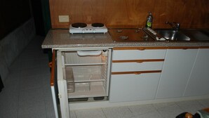 Una cocina compacta con estufa integrada, lavaplatos y refrigerador.