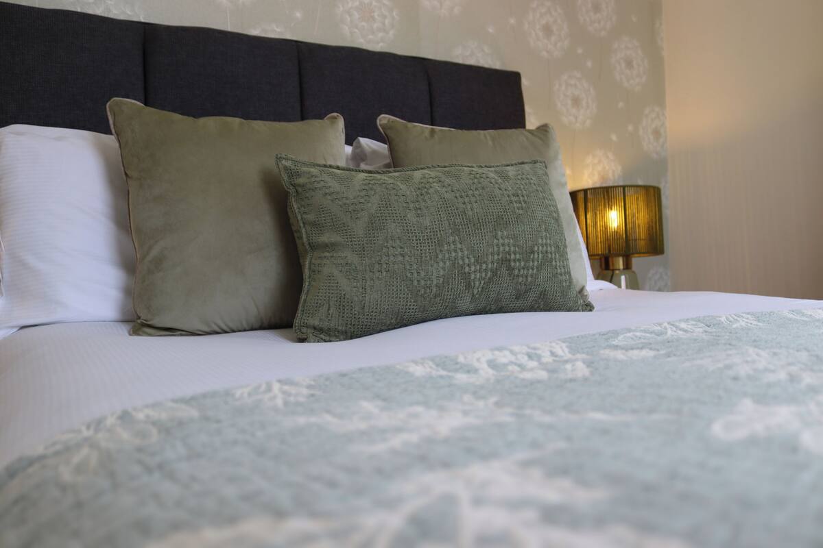 A neatly made bed with a patterned bedspread and two pillows.