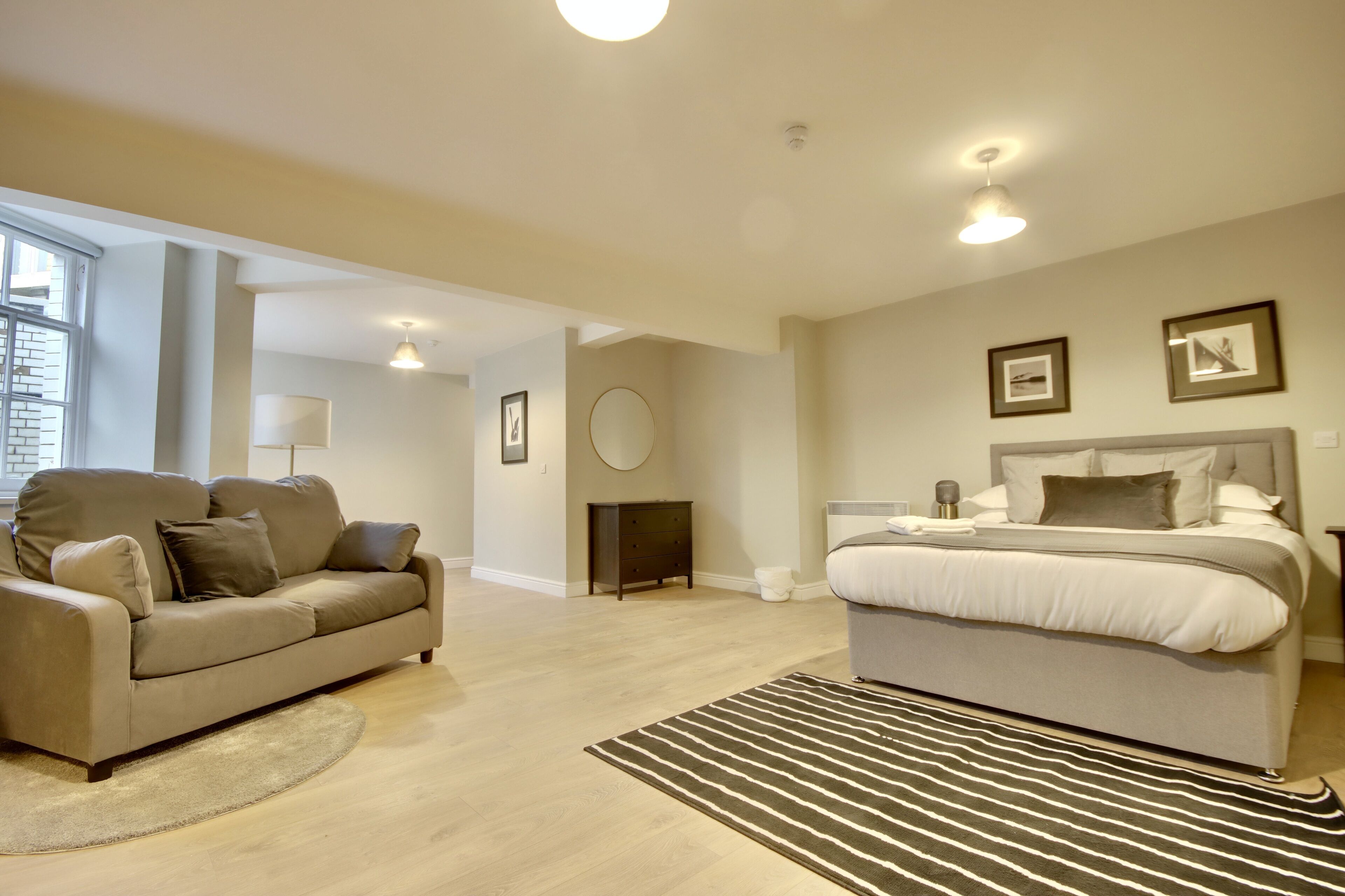 A modern bedroom with a large bed, a sofa, and a small round table.