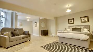 A modern bedroom with a large bed, a sofa, and a small round table.