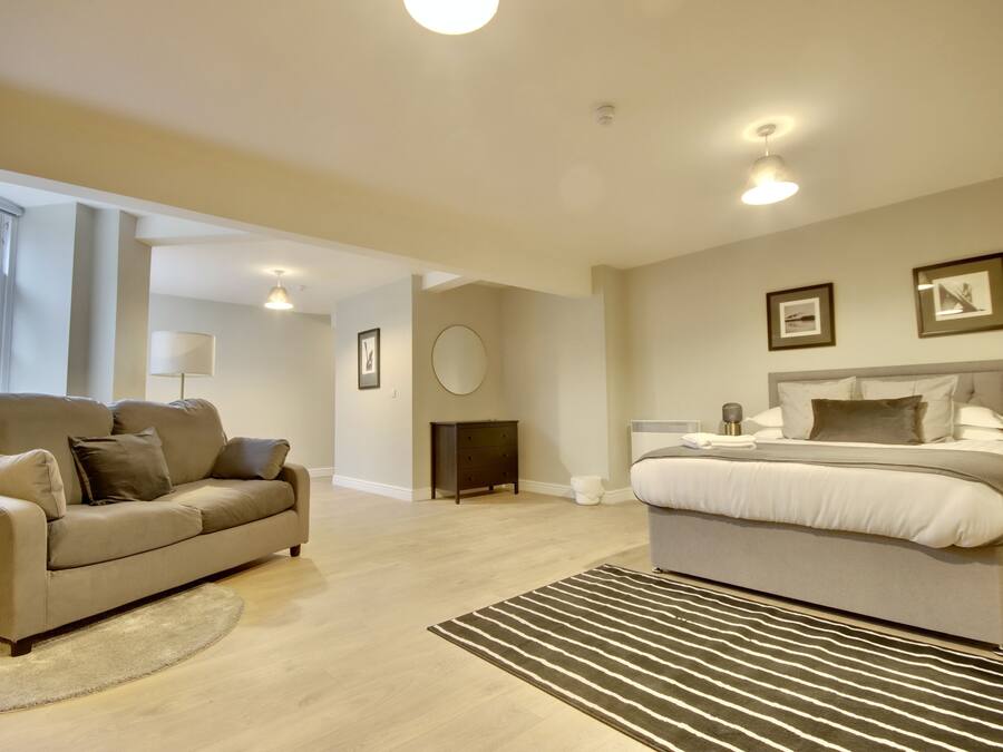 A modern bedroom with a large bed, a sofa, and a small round table.