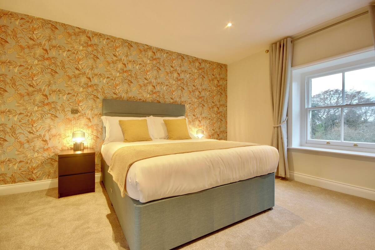 A bedroom with a bed, nightstands, and a window.