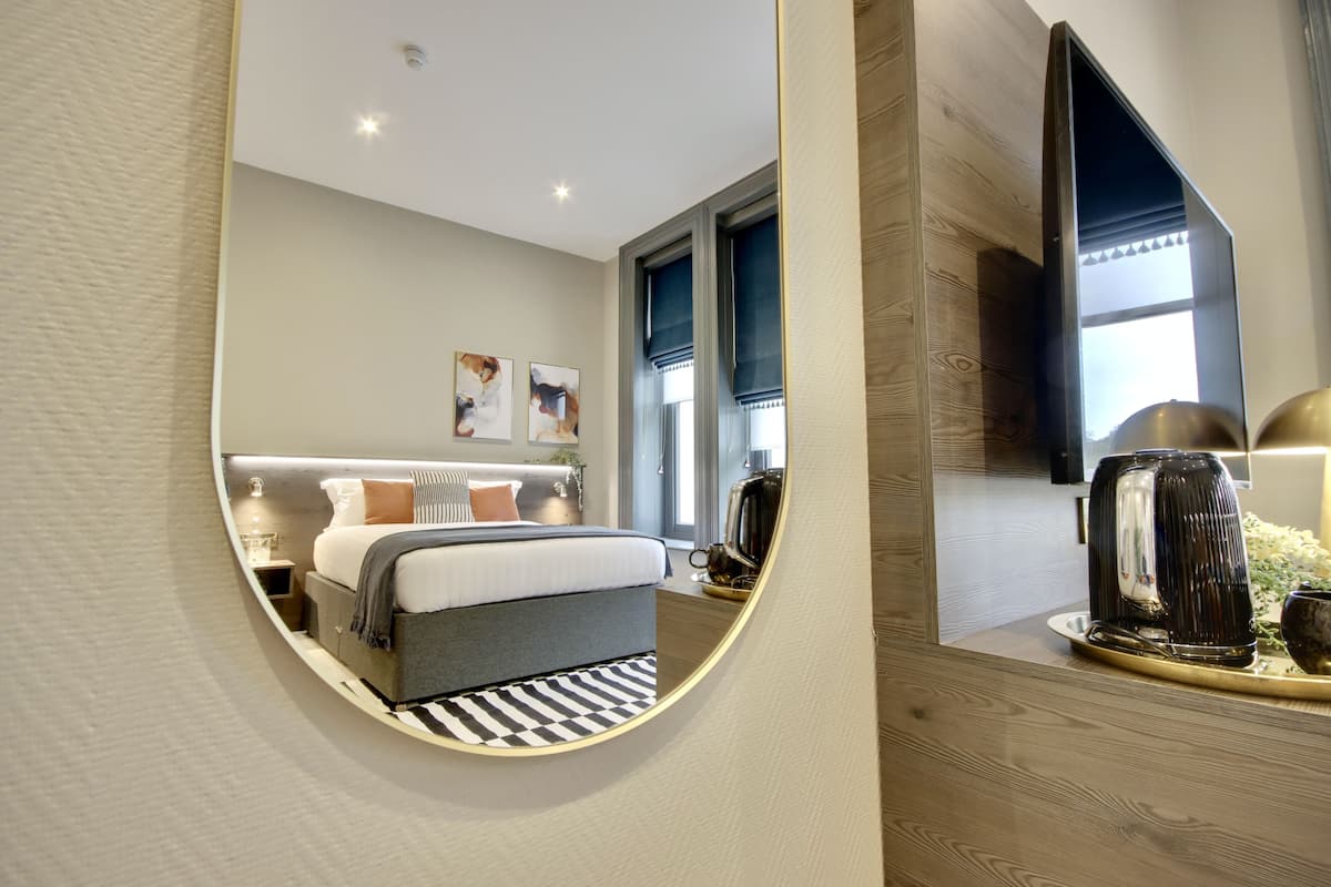 A modern hotel room with a bed, bedside table, and a flat-screen TV mounted on the wall.