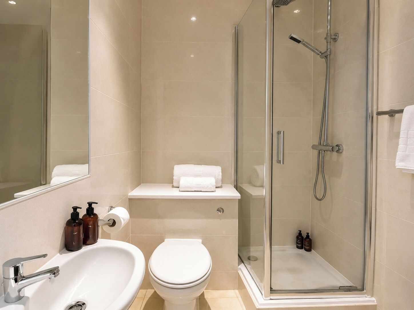 Ein modernes Badezimmer mit einer gläsernen Duschkabine, einem weißen Waschbecken und einer Toilette.