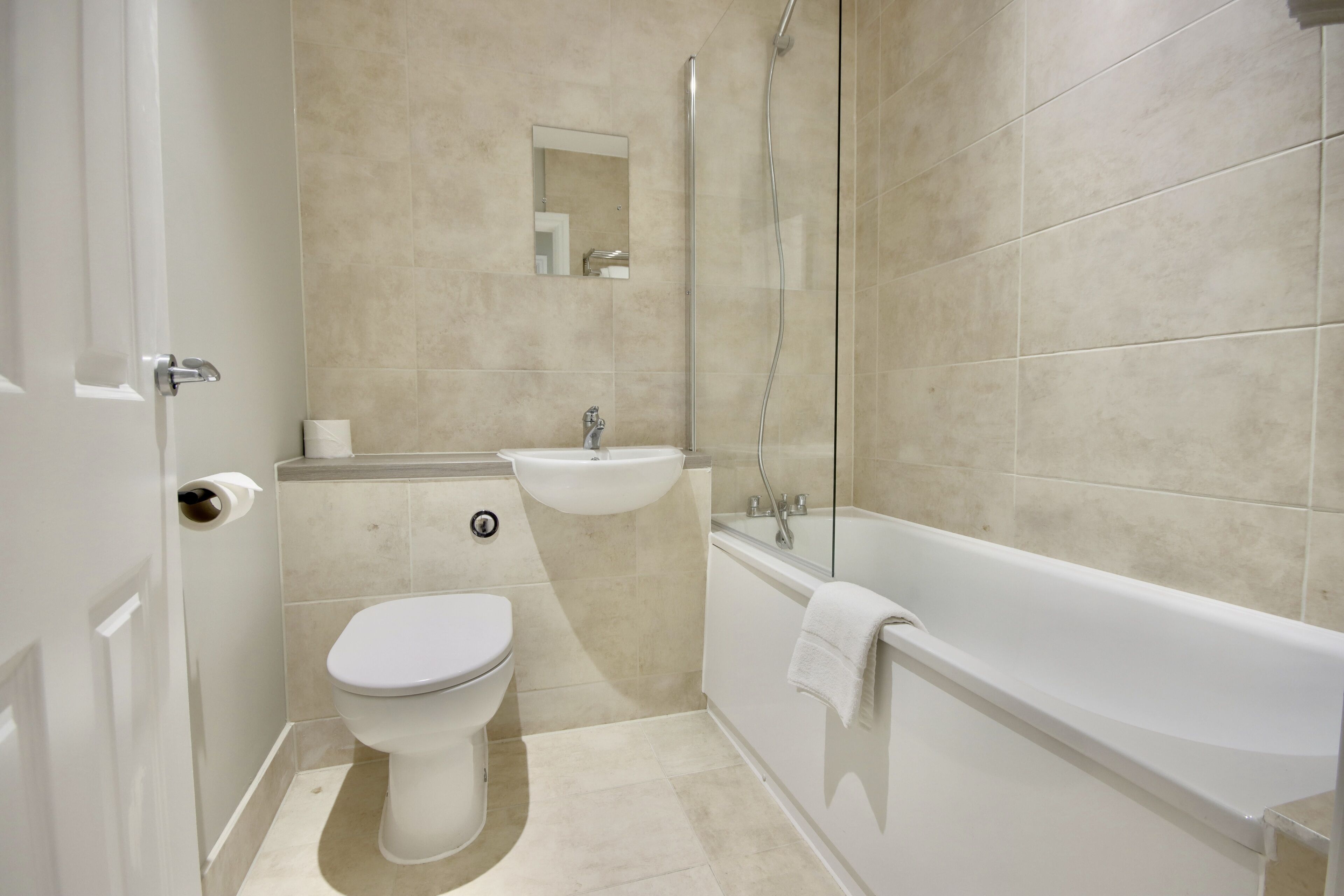 Et badeværelse med toilet, vask og badekar.