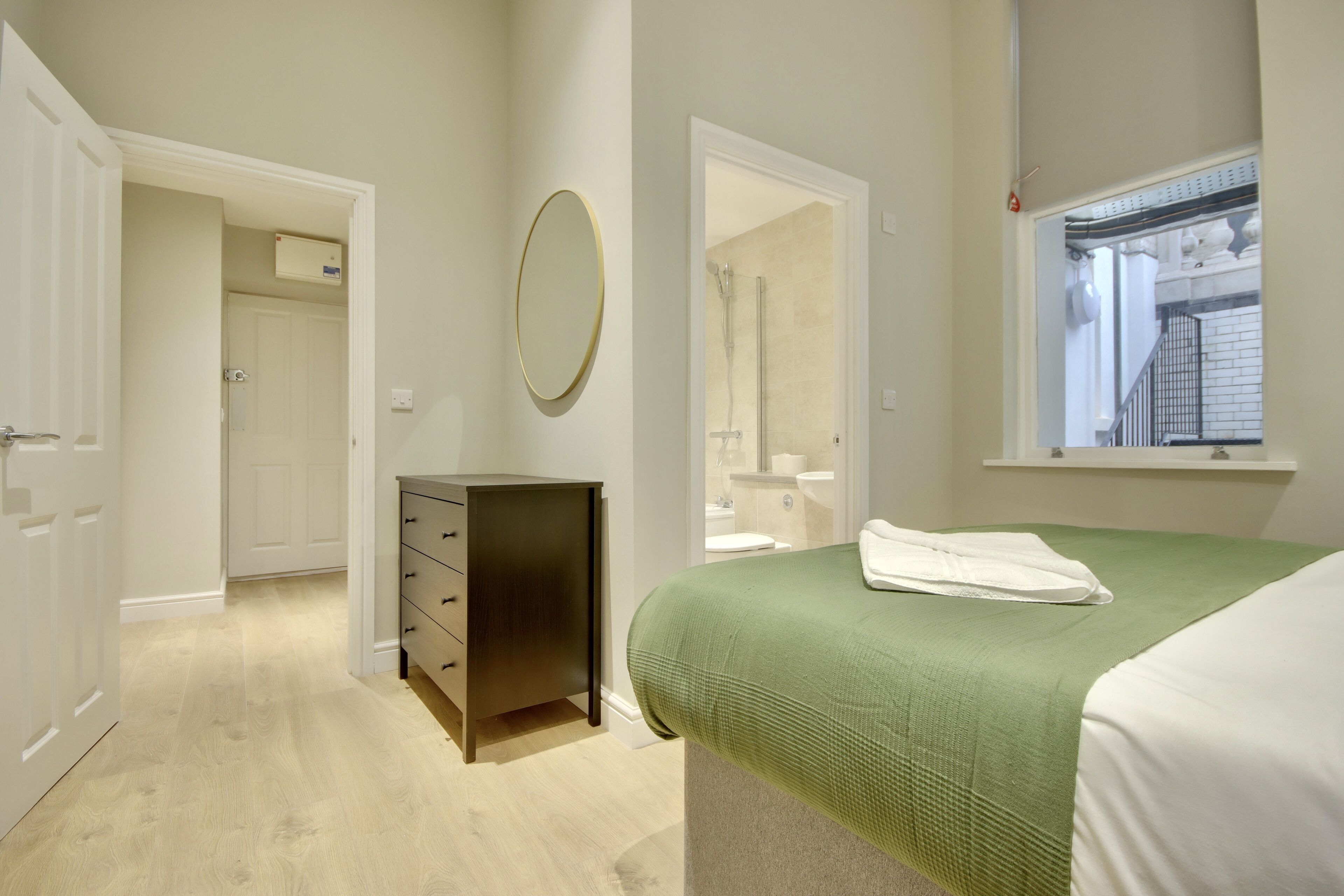 A bedroom with a bed, a dresser, a mirror, and a window.