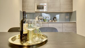 Cozinha com micro-ondas e uma garrafa de vinho sobre um jogo de chá.