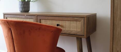 A wooden desk with a woven basket and a potted plant.