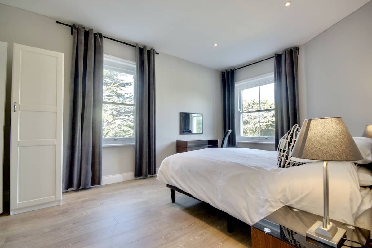 A modern bedroom with a bed, bedside lamp, and a TV on a stand.