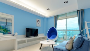 Un saló modern amb un sofà blau, una taula de centre rodona, televisió de pantalla plana i un balcó amb vistes.