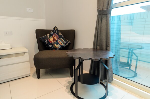 A modern room with a brown chair, a small round table, and a window with blinds. - Taiping 528 B&B (Beinan)