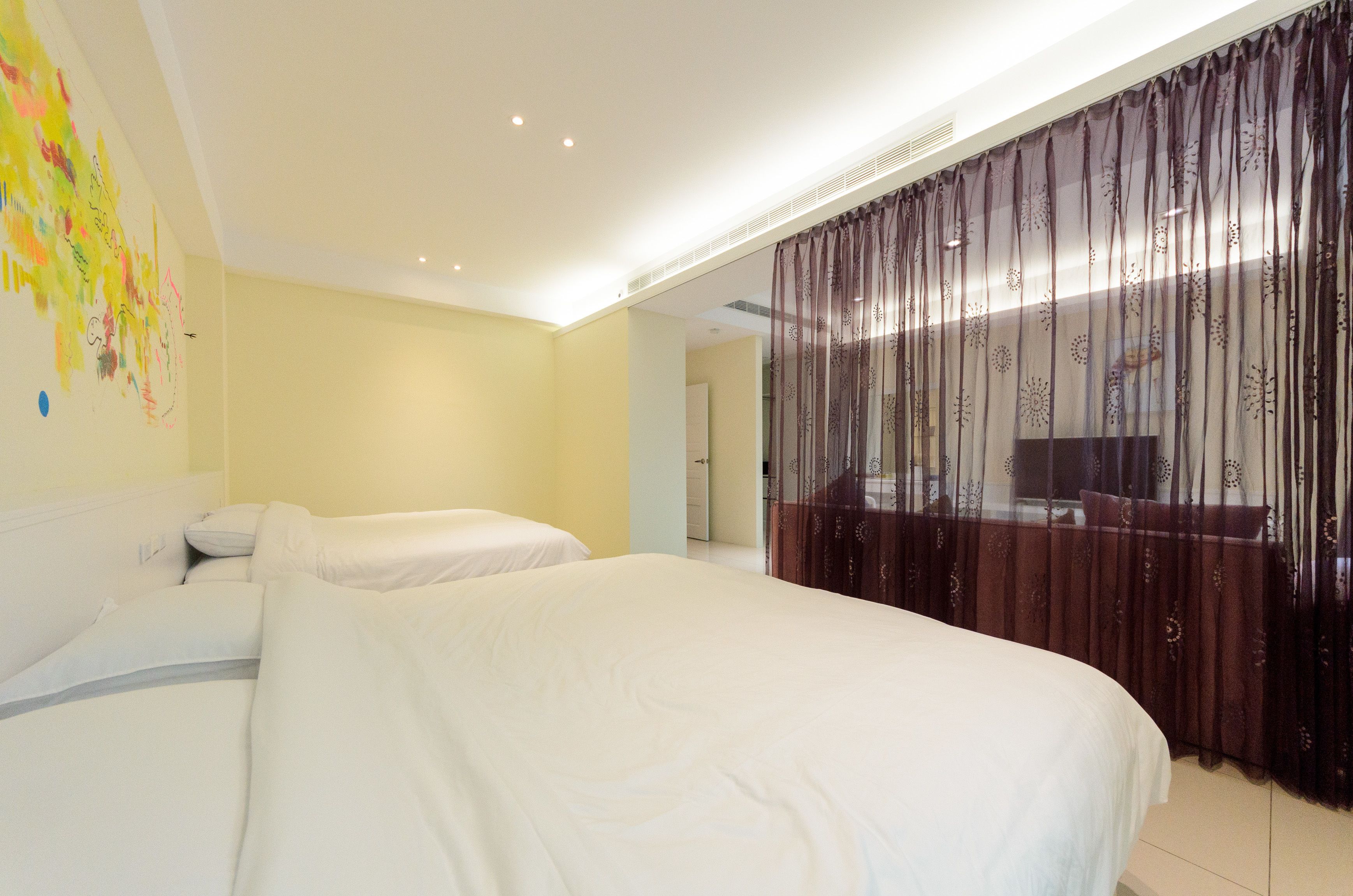 A hotel room with two beds, a large window with sheer curtains, and a wall with abstract art.