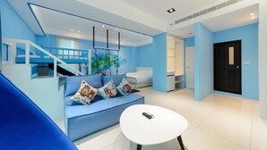 Un saló modern amb un sofà blau, una taula de centre blanca i una escala que condueix a un nivell superior.