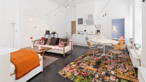 Una sala de estar moderna con un sofá, una mesa de comedor y una cocina al fondo.