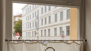 Vista a través de una ventana con cortina, mostrando una escena urbana con edificios y señales de tráfico.