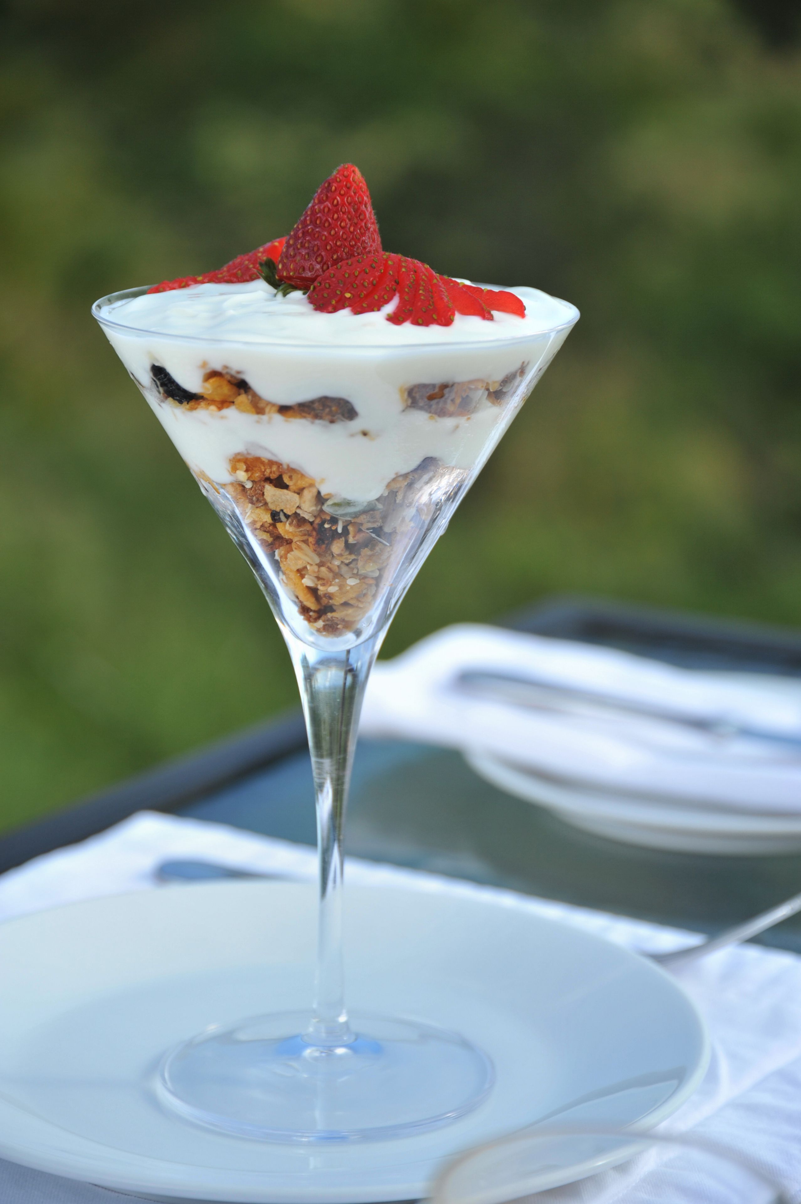 A dessert in a martini glass on a white plate.