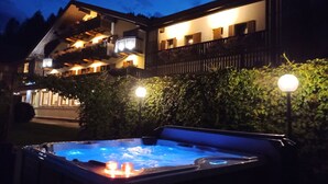A building with a hot tub and outdoor lighting. - Park Hotel Arnica (Falcade)