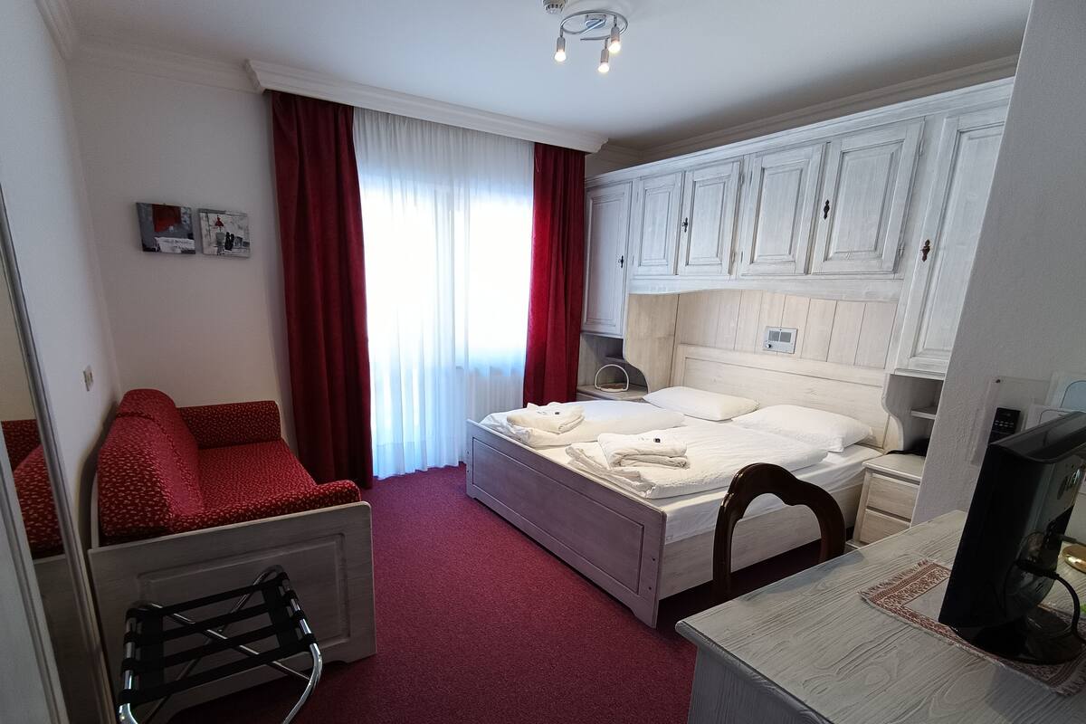 Una habitación de hotel con cama, escritorio, silla y televisor.