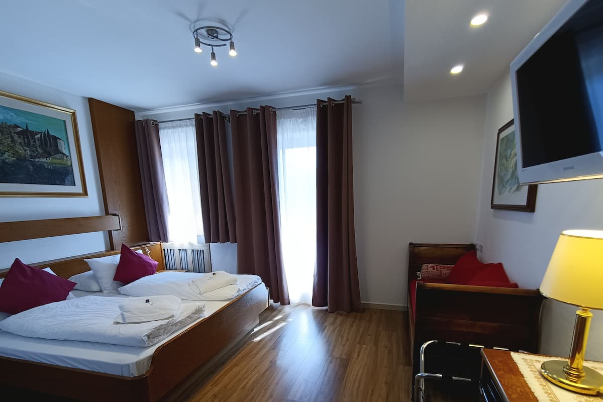 Habitación de hotel con cama, escritorio, silla, televisor y un cuadro en la pared.