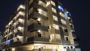 Un hotel de varios pisos con balcones, entrada a nivel de calle y una luna visible en el cielo.