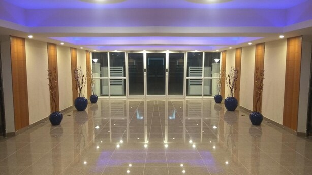 Un hall espacioso con piso pulido, puertas correderas de vidrio y jarrones decorativos.