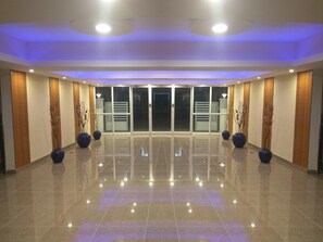 Un hall espacioso con piso pulido, puertas correderas de vidrio y jarrones decorativos.