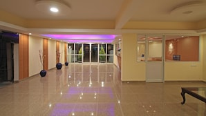 Un vestíbulo amplio con suelo pulido, una recepción y una entrada con puerta de cristal.