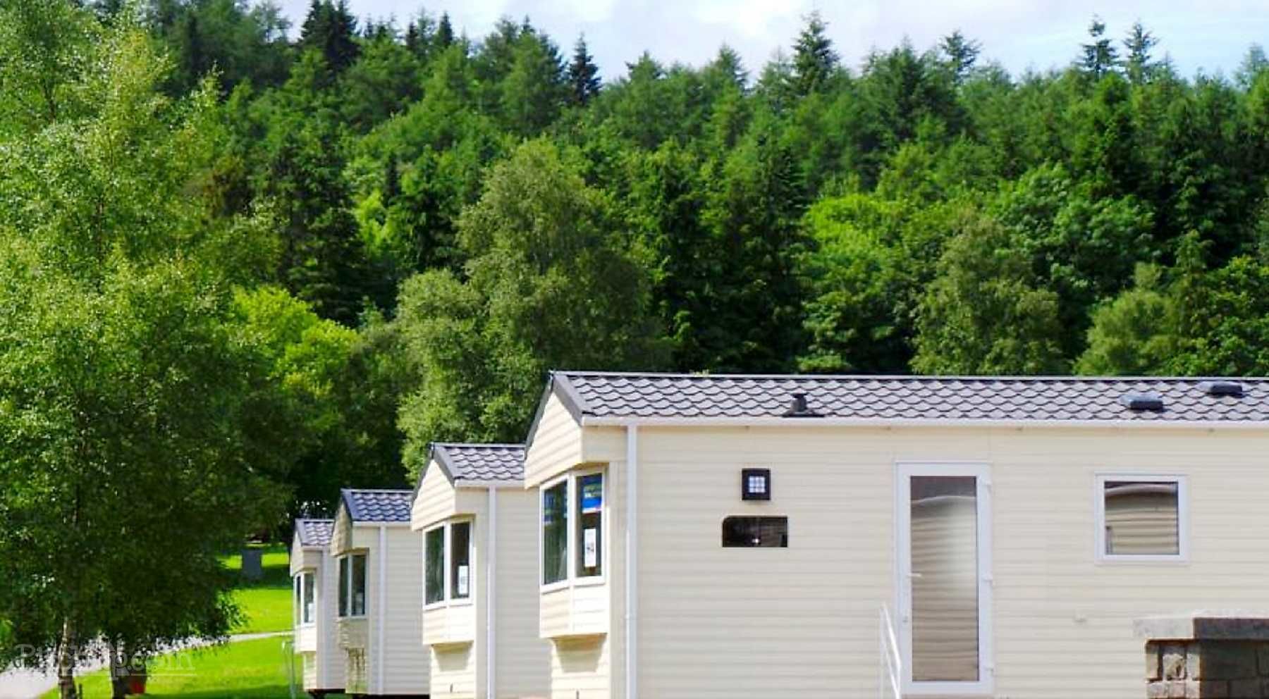 Una hilera de casas móviles con un paisaje boscoso al fondo.