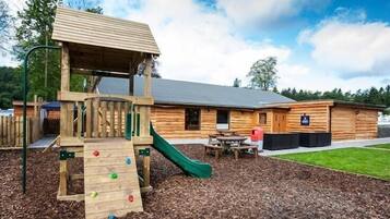 Children can play on the climbing structure and slide in this outdoor play area adjacent to a cozy cabin.