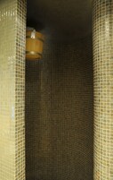 Una ducha con azulejos y un cubo de madera colgando del techo.