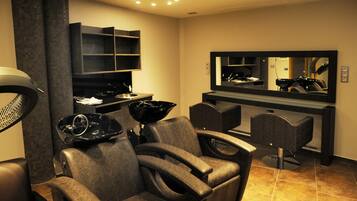 A modern hair salon with leather chairs, a large mirror, and a hairdryer.