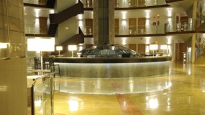 A spacious lobby with a central glass fountain, multiple floors, and a modern design. - Cumbria Spa & Hotel (Ciudad Real)