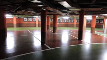 An indoor shooting range with multiple lanes, orange pillars, and targets.