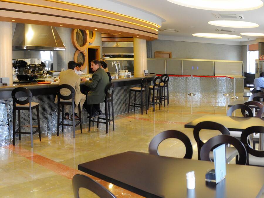 Ein modernes Restaurant mit Bar, Sitzgelegenheiten und einer Küche im Hintergrund.