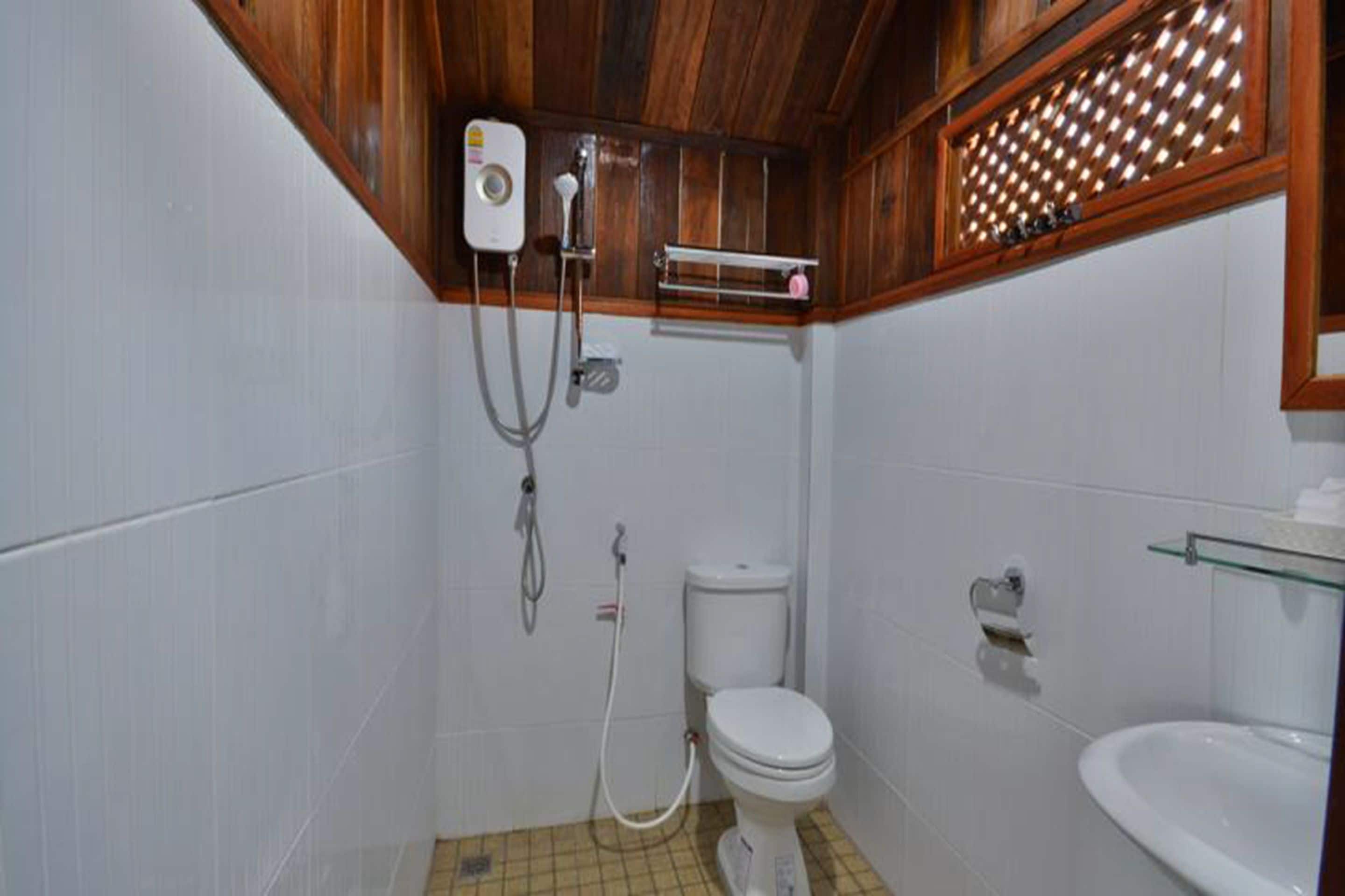 Uma casa de banho pequena com sanita, chuveiro e lavatório.