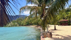Una playa con agua turquesa cristalina, palmeras y una estructura de madera.