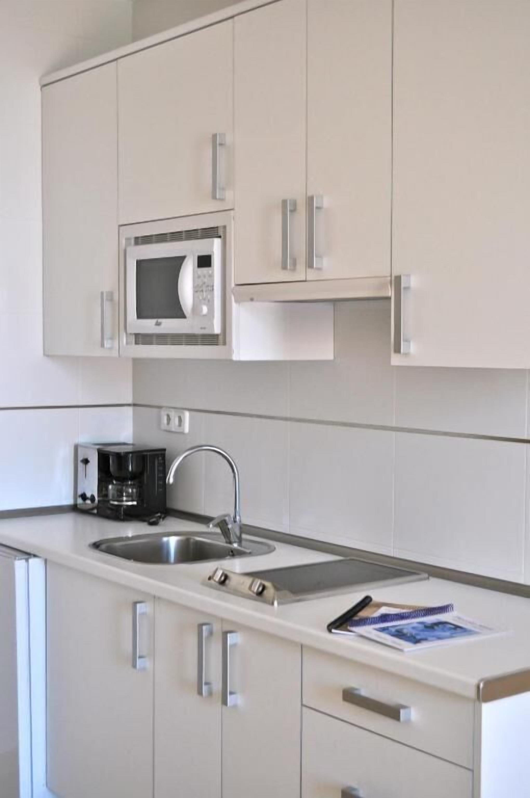 A kitchen with a microwave, coffee maker, and double sink.
