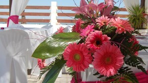 A table with a pink floral arrangement, white tablecloth, and a wooden pergola structure in the background. - El Secreto del Agua (Cartagena)
