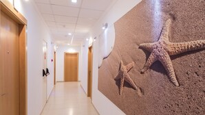 A hotel hallway with wooden doors, a tiled floor, and a wall mural of starfish. - El Secreto del Agua (Cartagena)