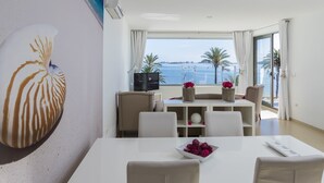 A modern dining area with a white table, beige chairs, and a view of the sea through large windows. - El Secreto del Agua (Cartagena)