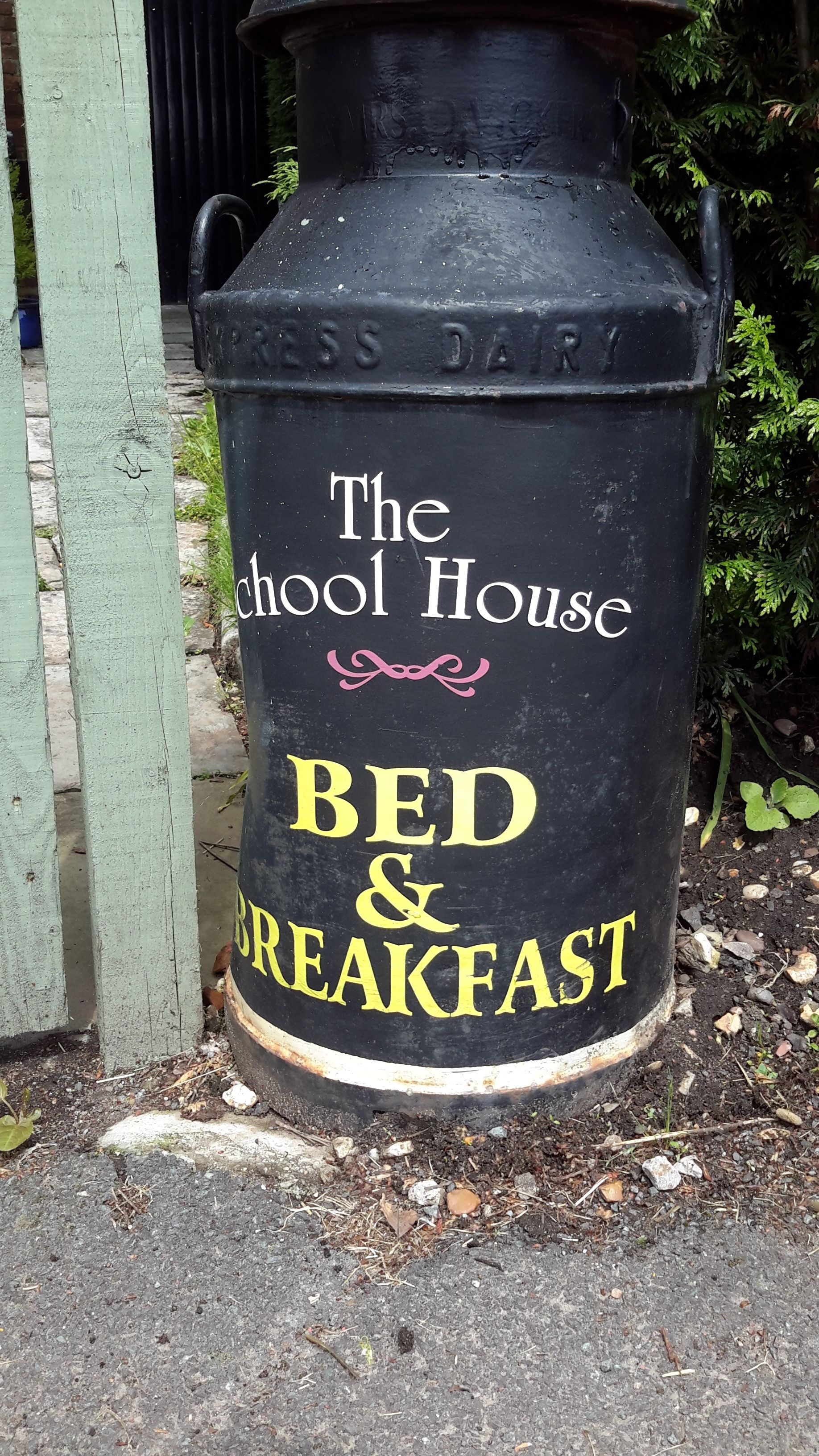 Ein schwarzer Container mit der Aufschrift 'The School House BED & BREAKFAST' und rustikalem Design.