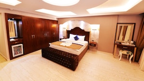 Un dormitorio moderno con una cama grande, un armario de madera, un mueble pequeño y un tocador con espejo.