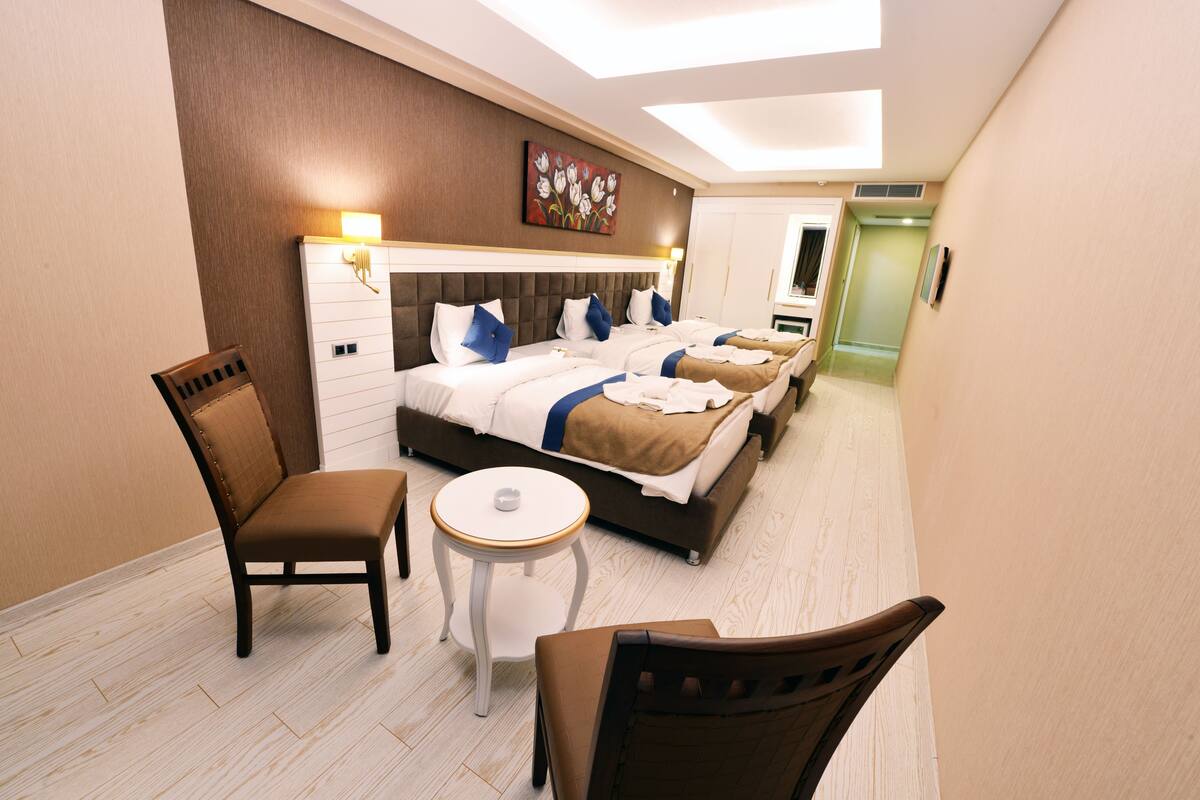 Une chambre d’hôtel avec un grand lit, deux tables de chevet, une chaise et une petite table.