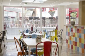 A restaurant with a view of the street, featuring colorful chairs and tables. - Funway Academic Resort - Adults Only (Madrid)
