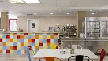 A modern kitchen with a colorful tile backsplash, stainless steel appliances, and a variety of seating options including chairs and a table.