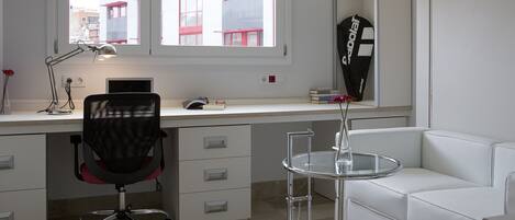 A modern office space with a desk, chair, and a white sofa.