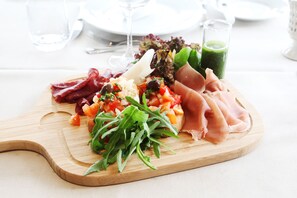 A wooden board with various food items including meats, vegetables, and a green sauce. - Fangel Kro & Hotel (Odense)