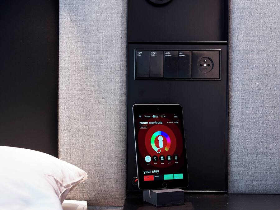 A modern room with a control panel for lighting and a smartphone displaying room controls.