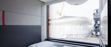 Una habitación de hotel moderna con una cama grande, vista a una obra en construcción y una lámpara de techo original.