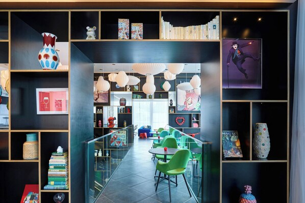 A modern library with bookshelves, a central reading area with chairs, and decorative items.
